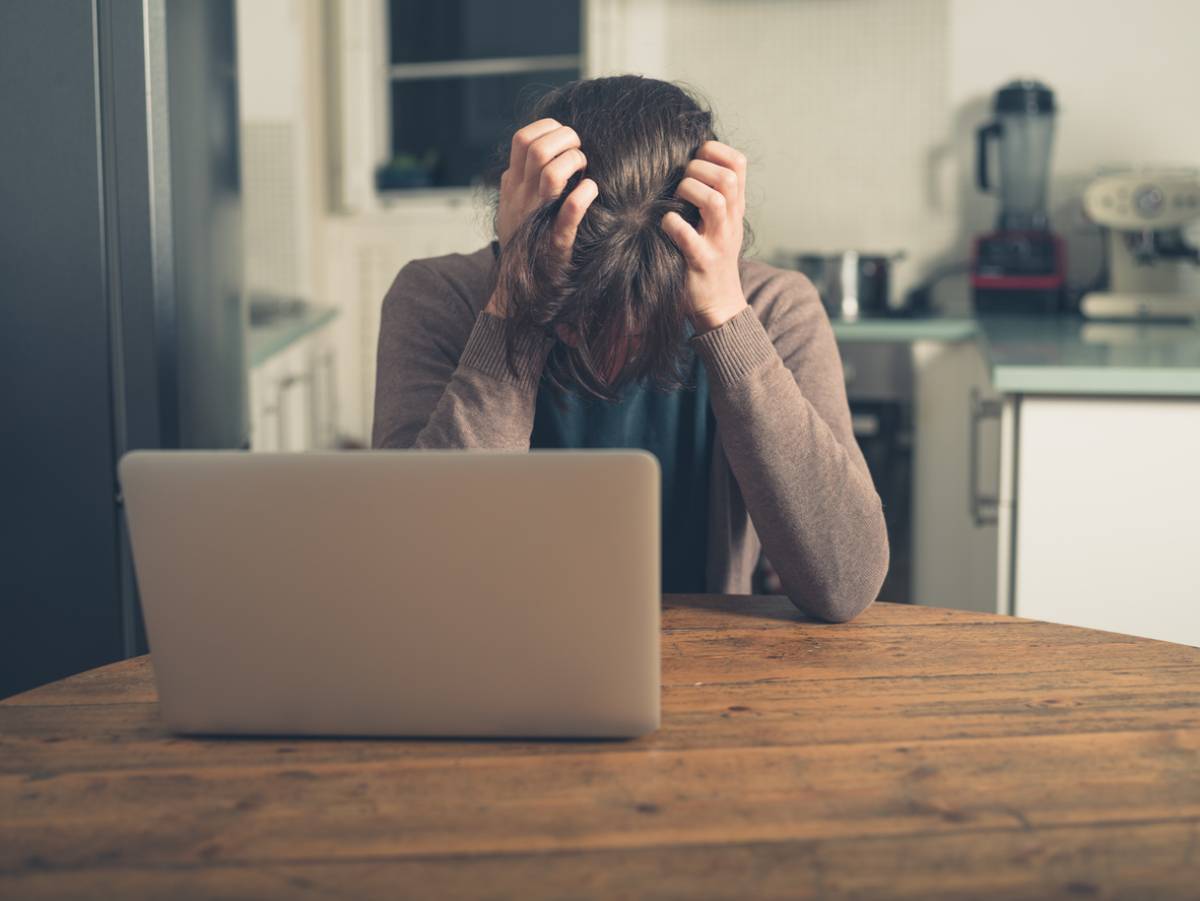 Person sitting at table trying to pull out their hair.